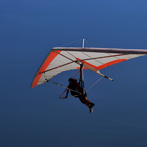 Uma pessoa voando de asa delta contra um ceu azul